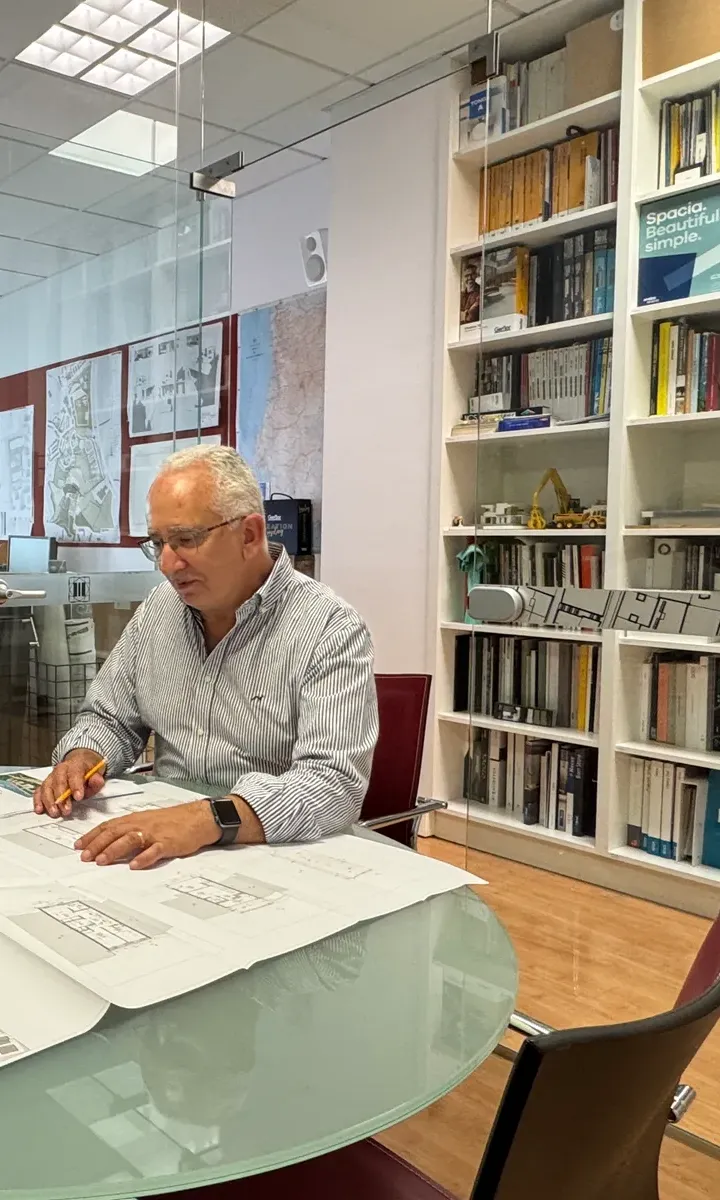 Arquiteto do Atelier Geometria a analisar plantas na sala de reuniões