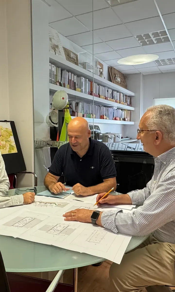 Três elementos da equipa em reunião de projeto sobre desenhos técnicos