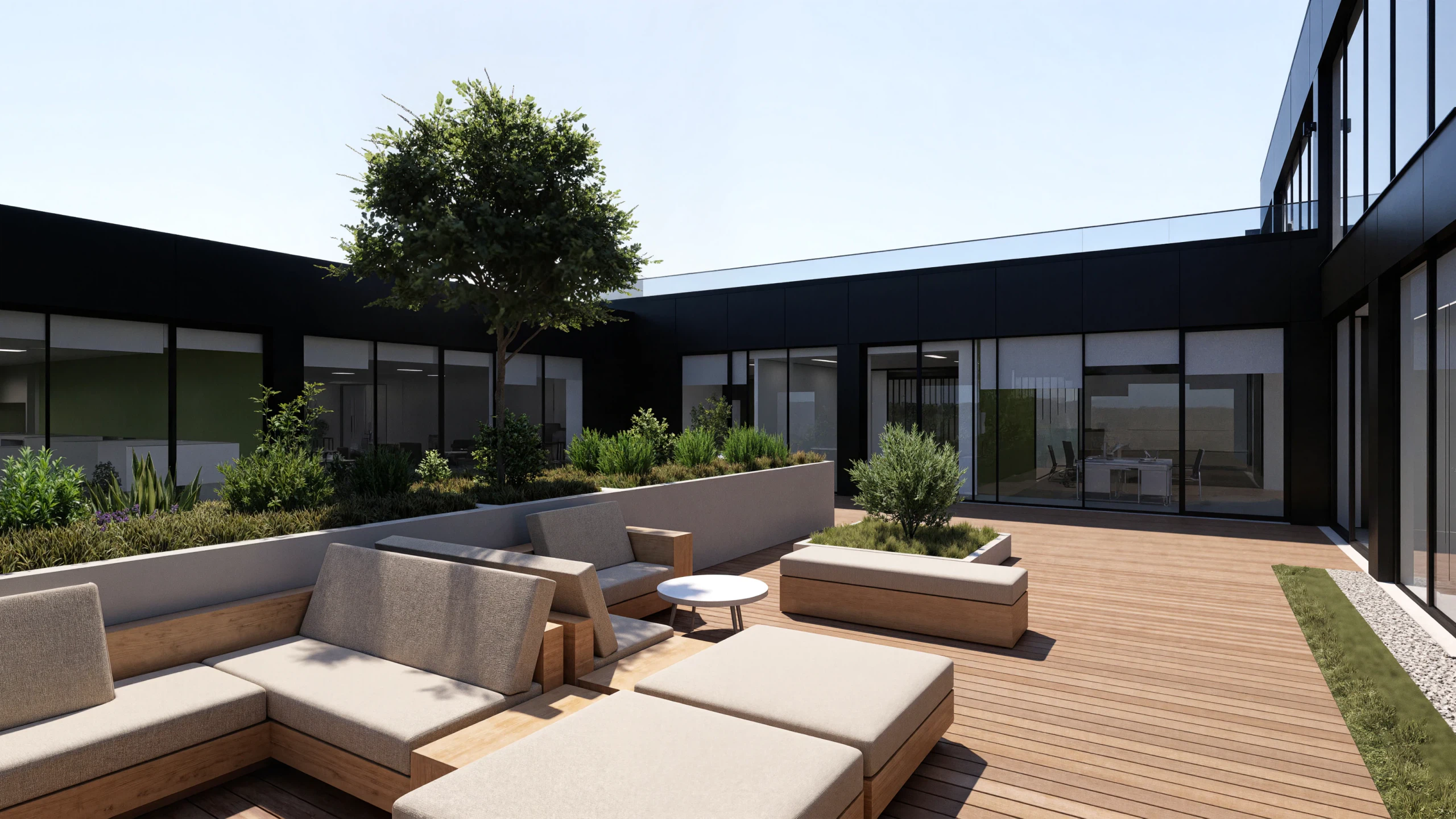 Terraço do primeiro andar, aberto no vazado central do volume: deck de madeira, bancos corridos e canteiros com uma árvore ao centro, rodeados em três frentes pelos envidraçados dos escritórios.