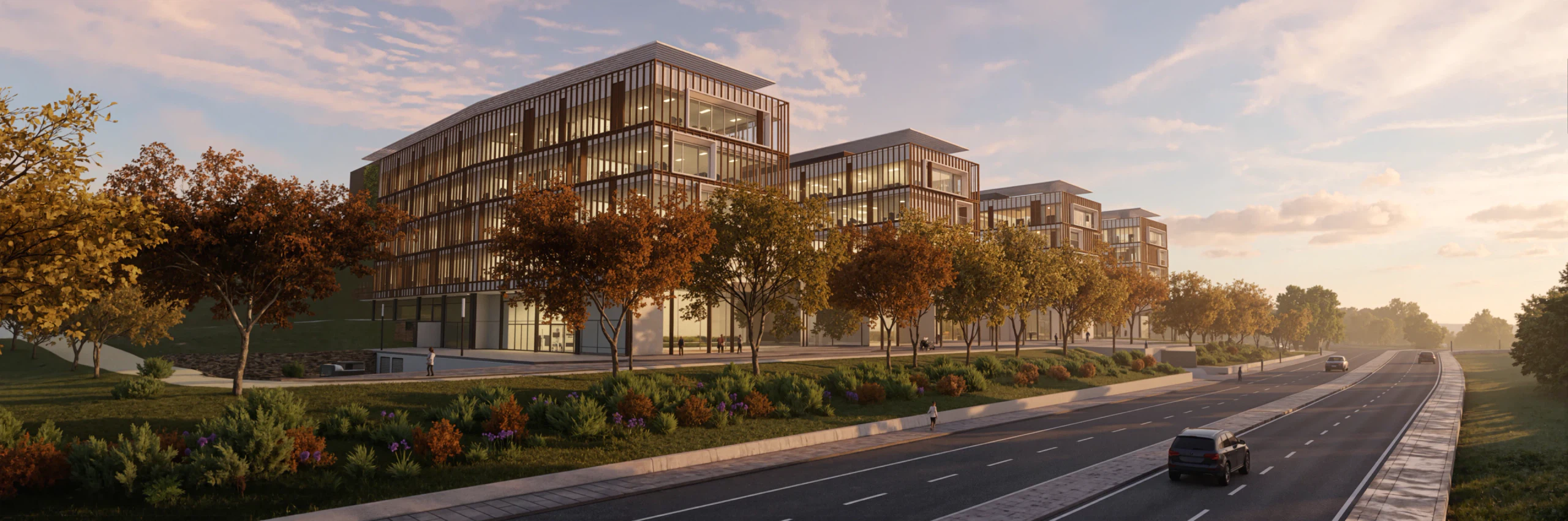 A frente do parque empresarial de Loures ao fim da tarde, com o alinhamento de árvores à face do edificado e a EN8 reperfilada a correr para o horizonte, já com separador plantado e faixa ciclável.